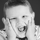Young boy laughing with hands on cheeks