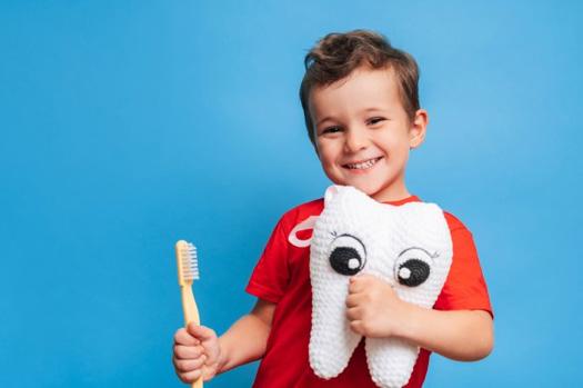 Child smiling and holding a tooth plushie 