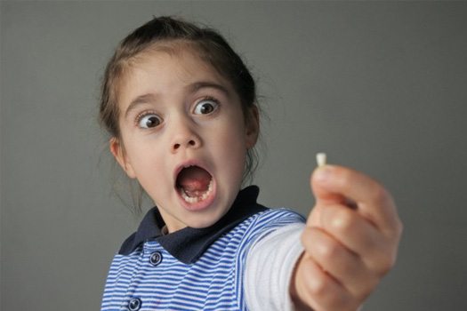 Child holding a knocked-out tooth looks surprised 