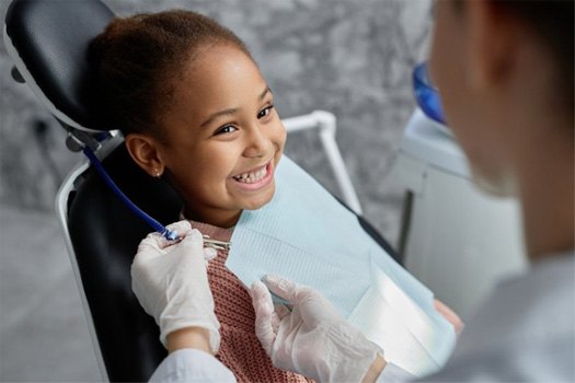 Child smiling as dentist gets ready to examine her teeth