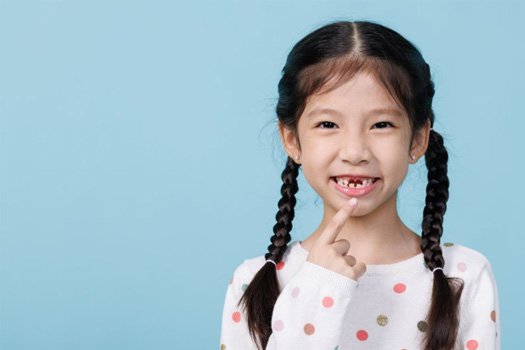 : Child pointing to two missing teeth