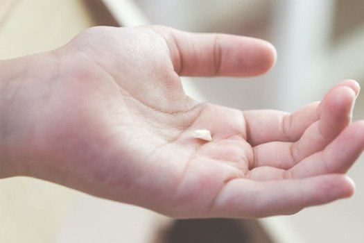 Close up of a small tooth sitting in a dentist’s palm