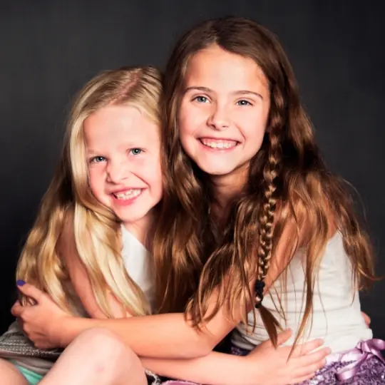 Two young girls grinning and hugging