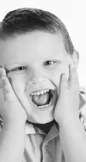 Child with wide open mouth holding their face with their hands