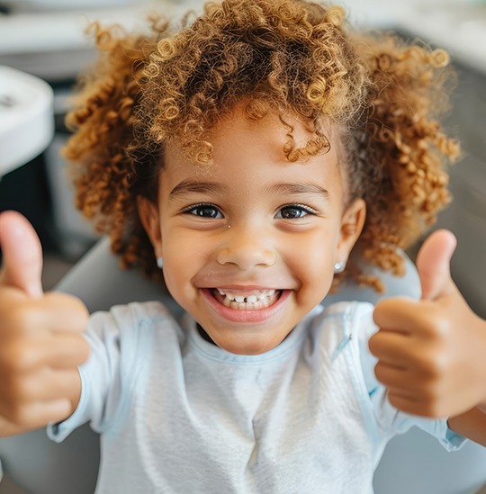 Little girl giving a thumbs up after a dental checkup