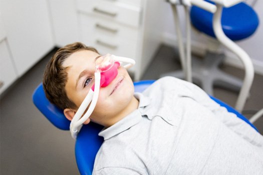 Little boy with pink nitrous oxide mask over nose