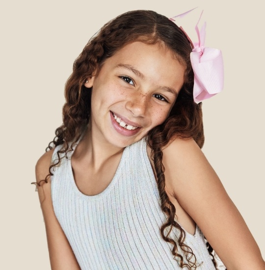 Girl with glasses and backpack smiling after seeing pediatric dentist in Hinsdale and Downers Grove