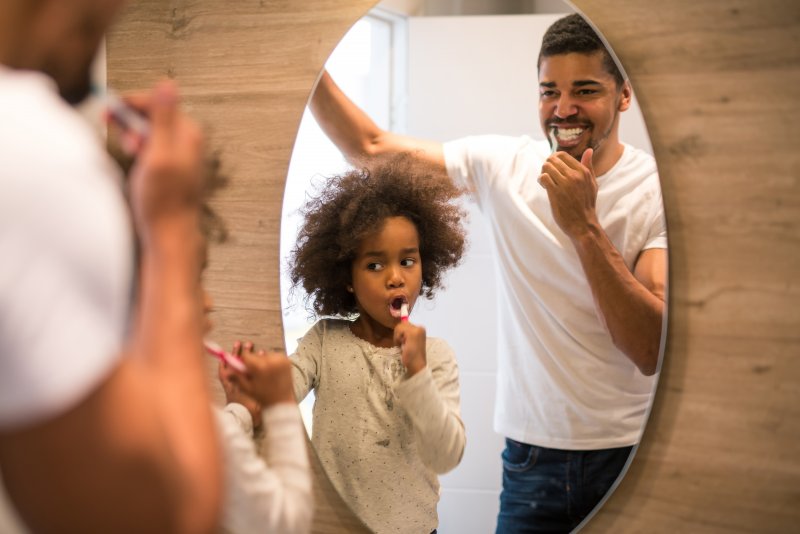 father and daughter brushing their teeth