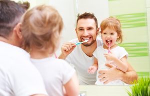 Dad praising young daughter for brushing her teeth
