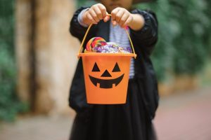 a child holding a bucket of Halloween candy