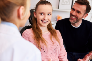 a parent and teen speaking with a pediatric dentist