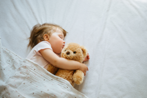 a baby sleeping with a teddy bear