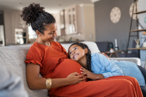 a child laying her head on her pregnant mom's belly